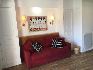 a red couch in a living room with a painting of baseball players at Appartement cosy à Saint-André-des-Eaux de 47 m² avec jardin in Saint-André-des-Eaux