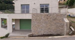 a house with a green door and a stone wall at Maison confortable avec vue sur la mer et la montagne à Oletta. in Oletta