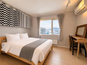 a bedroom with a bed and a desk and a window at The Lobs 2, Rusutsu, Yotei view, 8 mins to Rusutsu in Kimobetsu