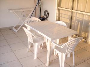 a white table with four white chairs around it at Appartement face à la mer à La Trinité – 70 m² – Terrasse in La Trinité