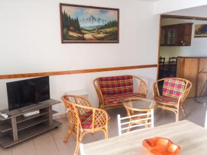 a living room with chairs and a tv and a table at Appartement lumineux aux Trois-Îlets in Les Trois-Îlets +4 photos
