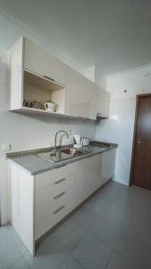 a white kitchen with a sink and a counter at Modern apartment in Estói with shared pool. in Estói