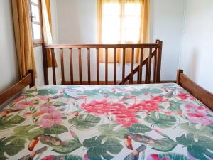 a bed with a colorful bedspread with birds on it at Appartement confortable au Robert 70 m² avec jardin privé in Le Robert