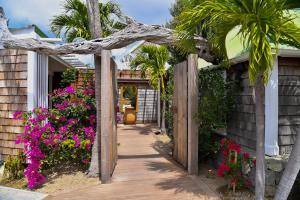 a wooden walkway leading to a house with pink flowers at Exceptional villa with pool and spa, Saint-Barthélemy. in Saint Barthelemy