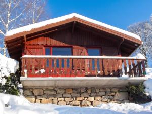 a log cabin with a red door in the snow at Chalet charmant au Tholy avec piscine partagée in Le Tholy