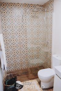 a bathroom with a toilet and a tiled wall at Charming House in Sistelo + View in Sistelo +4 photos
