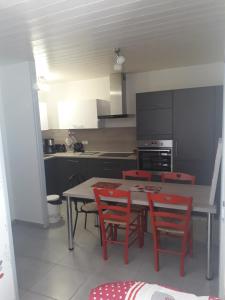 a kitchen with a table and red chairs in it at Appartement cosy avec piscine privée à Métabief - 38 m² in Métabief