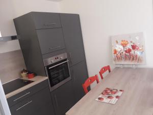 a kitchen with a black refrigerator and a table at Appartement cosy avec piscine privée à Métabief - 38 m² in Métabief