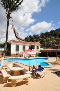 a person laying in a chair next to a swimming pool at Apartamentos Buen Leon in Playa de Tasarte