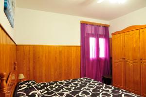 a bedroom with a bed and a purple curtain at Apartamentos Buen Leon in Playa de Tasarte