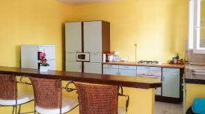 a kitchen with a counter with chairs and a refrigerator at Appartement Privilégié Le Moule 70 m² + Piscine in Le Moule