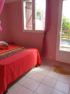 a bedroom with a red bed and a window at Appartement Privilégié Le Moule 70 m² + Piscine in Le Moule +10 photos
