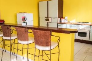 a kitchen with a counter with four bar stools at Appartement Privilégié Le Moule 70 m² + Piscine in Le Moule