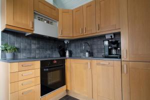 a kitchen with wooden cabinets and a black appliance at Lake Cabin with Fireplace in Åre