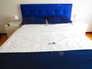 a large bed with a blue headboard and white sheets at Elegant Villa in Porto with Pool & Jacuzzi in Porto