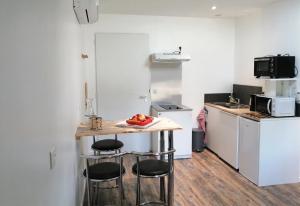 a small kitchen with a table and stools at Studio charmant à Saint-Jory, 25 m², piscine partagée in Saint-Jory