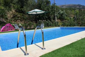 a pool with an umbrella and two chairs next to it at Peaceful villa in São Martinho de Mouros with private pool in Frende +29 photos