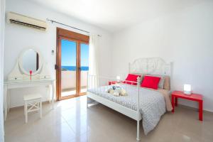 a white bedroom with a bed with red pillows and a mirror at Cosy House in Kiotari with Garden and Terrace in Kiotari