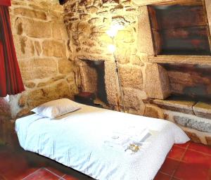 a bed in a room with a stone wall at Cozy house in Águeda 45 m² with shared pool in Urgueira
