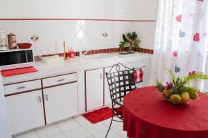 a kitchen with a red table and a red table sidx sidx sidx sidx at "Studio charmant à Deshaies avec piscine partagée, 20 m²" in Deshaies