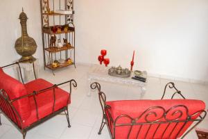 a living room with a red chair and a table at "Studio charmant à Deshaies avec piscine partagée, 20 m²" in Deshaies