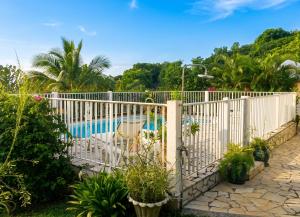 a white fence with a pool in the background at "Studio charmant à Deshaies avec piscine partagée, 20 m²" in Deshaies