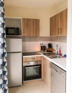 a kitchen with a white refrigerator and a sink at Maison confortable à Parentis-en-Born avec piscine partagée in Parentis-en-Born