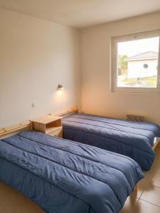 two beds in a room with a window at Maison confortable à Parentis-en-Born avec piscine partagée in Parentis-en-Born