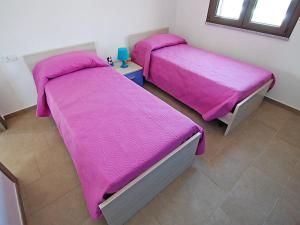 two beds in a room with pink sheets at Charming House in Is Potettus with Private Garden in SantʼAnna Arresi