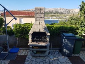 a stone fireplace in a yard with a trash can at Charming Apartment in Pag with Sea View, 40 sqm in Pag