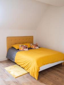 a bed with a yellow blanket and two pillows at Charmant studio à Abondant avec terrasse ensoleillée - 30 m² in Abondant