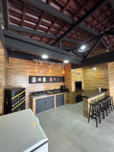 a large kitchen with wooden walls and tables and stools at Casa Completa em Picarras, Piscina, Sinuca e Churrasqueira in Piçarras