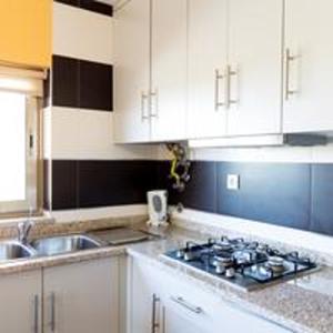 a kitchen with a stove and a sink and white cabinets at Comfortable Bungalow Pinhel, pool in Pinhel