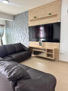 a living room with a couch and a flat screen tv at Casa Completa em Picarras, Piscina, Sinuca e Churrasqueira in Piçarras