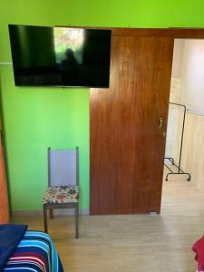 a room with a chair and a television on a wall at Recanto Pedrita in Pedreira