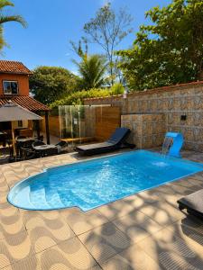 a swimming pool in a backyard with a stone wall at Pousada Viva Mar in Saquarema