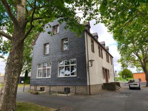a black and white house with a tree at Alte Schule Gästehaus - Klassenzimmer Loft in Bitburg