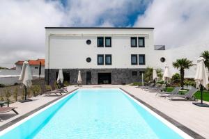 a swimming pool with chairs and a building at Gaivota Guest House in Ponta Delgada