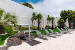 a row of chairs and umbrellas next to a building at Gaivota Guest House in Ponta Delgada