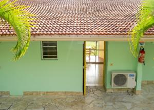 a green house with a white door and a fan at Studio confortable à Sainte-Anne - 30 m² avec vue mer in Sainte-Anne