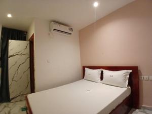 a bedroom with a white bed and a air conditioner at Kalis Hotel in Douala