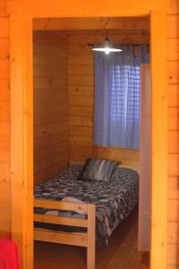a bed in a wooden cabin with a window at Charming bungalow in Tarifa with mountain view and garden in Tarifa