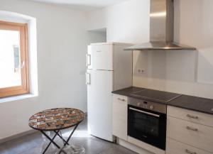 a kitchen with a refrigerator and a table and a chair at Appartement cosy à Bonifacio avec vue sur la mer - 45 m² in Bonifacio