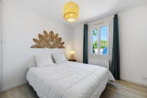 a bedroom with a white bed and a window at L'Epine Bleue in LʼÉpine