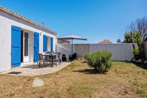 a patio with a table and chairs next to a house at L'Epine Bleue in LʼÉpine