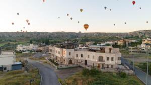 a group of hot air balloons flying over a building at Unique Cappadocia Palace in Göreme