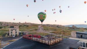 a bunch of hot air balloons flying over a building at Unique Cappadocia Palace in Göreme
