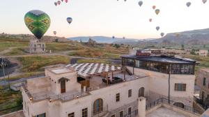 a bunch of hot air balloons flying over a building at Unique Cappadocia Palace in Göreme