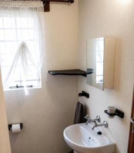 a bathroom with a sink and a mirror and a window at OPPIBERG GUEST HOUSE and SPA in Hartbeespoort +41 photos