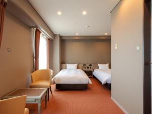 a hotel room with two beds and a table and chairs at Hotel Global View Nagaoka in Nagaoka